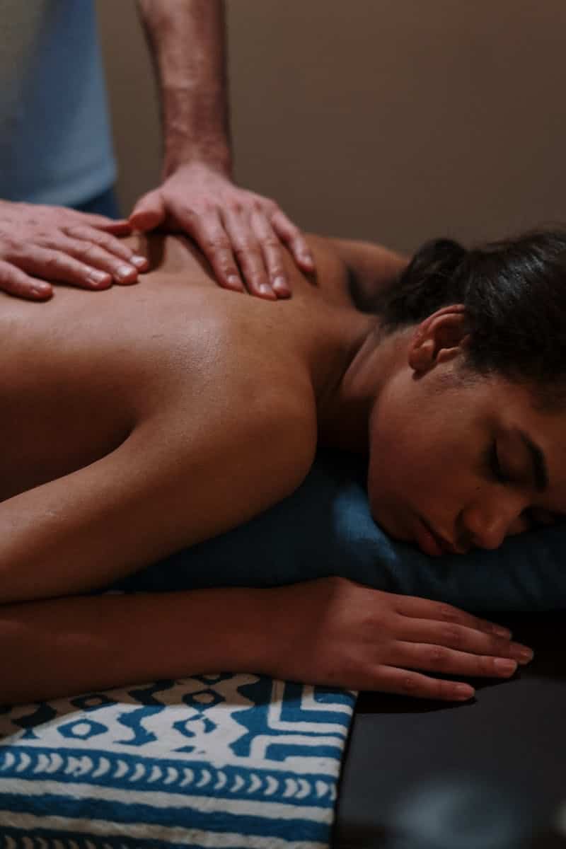 Relaxing massage therapy session with therapist's hands on woman's back in spa setting.